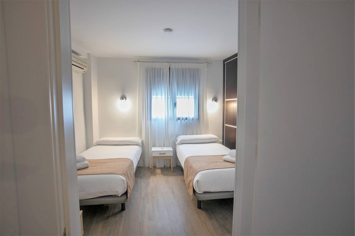 Een hotelkamer met twee enkele bedden, een klein nachtkastje en een grote spiegel.