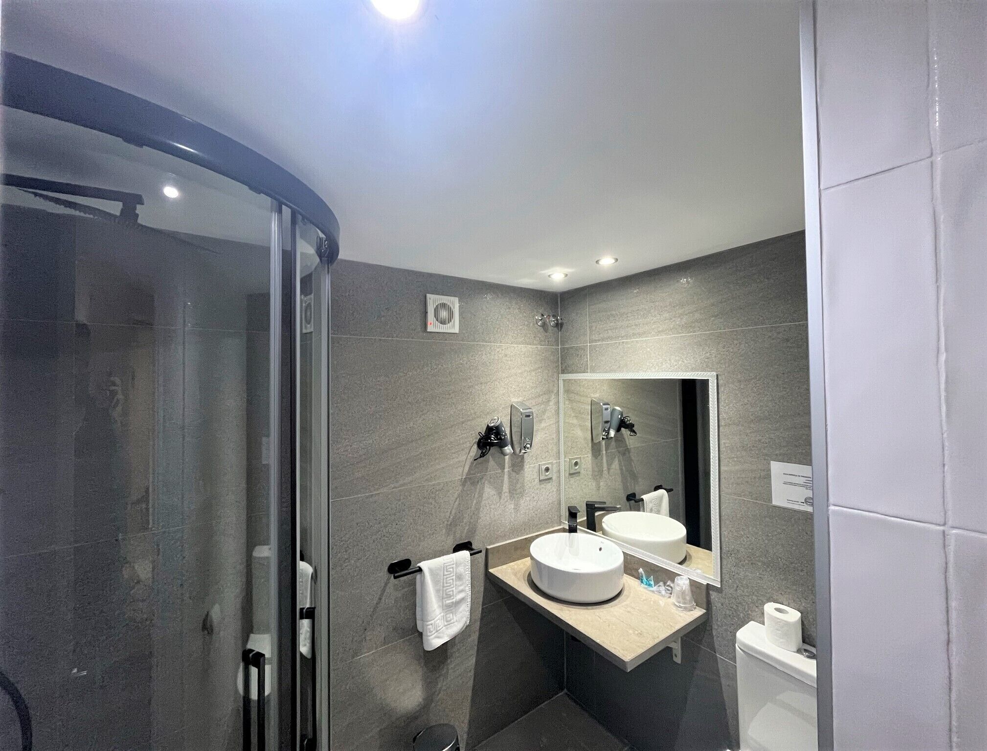 Un baño moderno con cabina de ducha de vidrio, tocador doble y un inodoro.