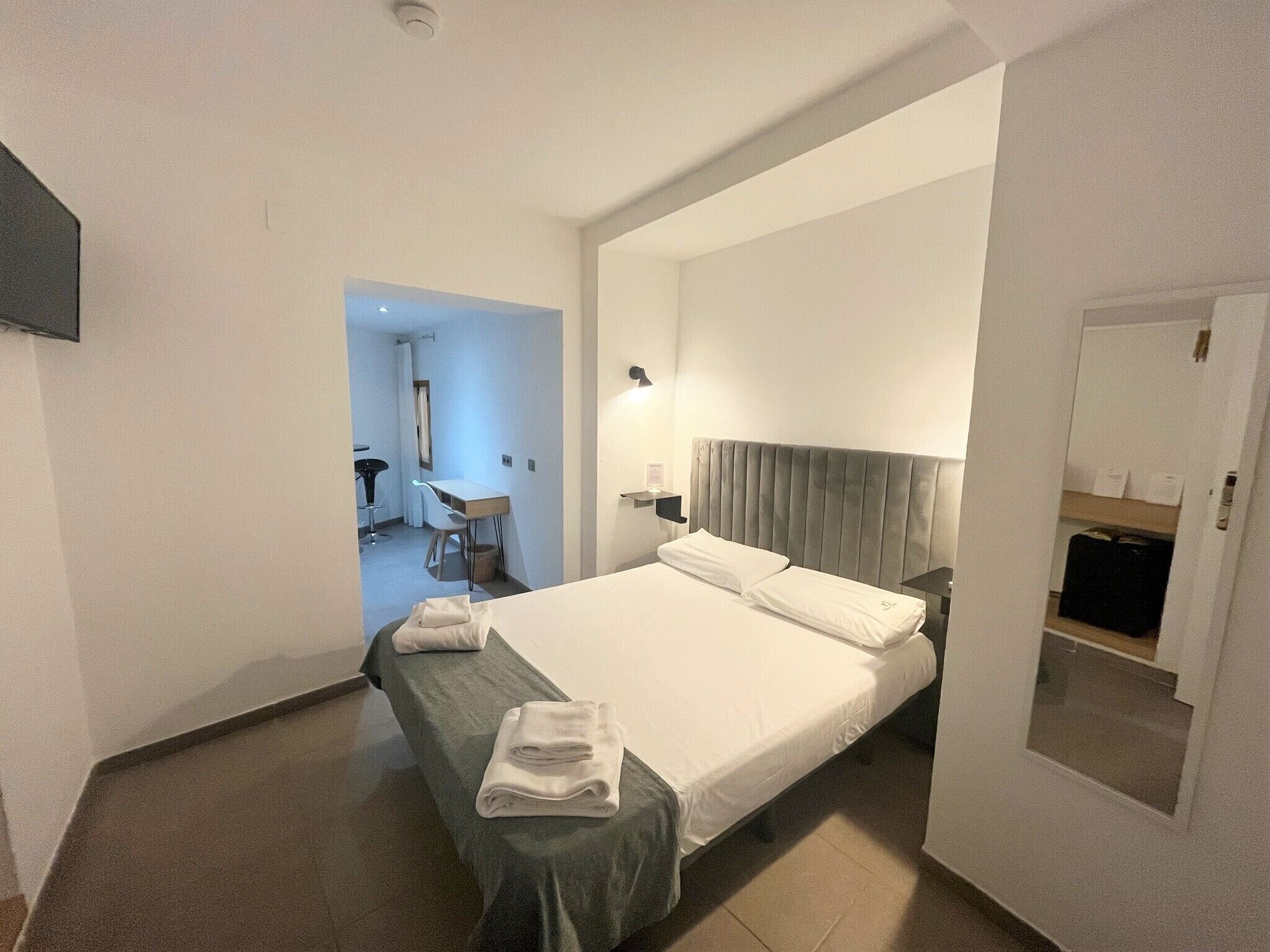 Una habitación de hotel con una cama grande, un escritorio y una silla.