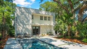 A modern house with a swimming pool, surrounded by lush greenery and palm trees. - Zen-N-Sea offers poolside relaxation and near the beach entrance, sleeps 8 (St Simons Island)