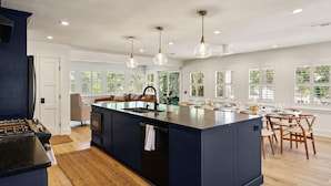 A modern kitchen with a central island, wooden flooring, and pendant lighting. - Zen-N-Sea offers poolside relaxation and near the beach entrance, sleeps 8 (St Simons Island)