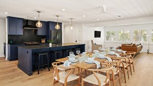 A modern kitchen with dark blue cabinets, a central island with stools, and pendant lighting. - Zen-N-Sea offers poolside relaxation and near the beach entrance, sleeps 8 (St Simons Island)