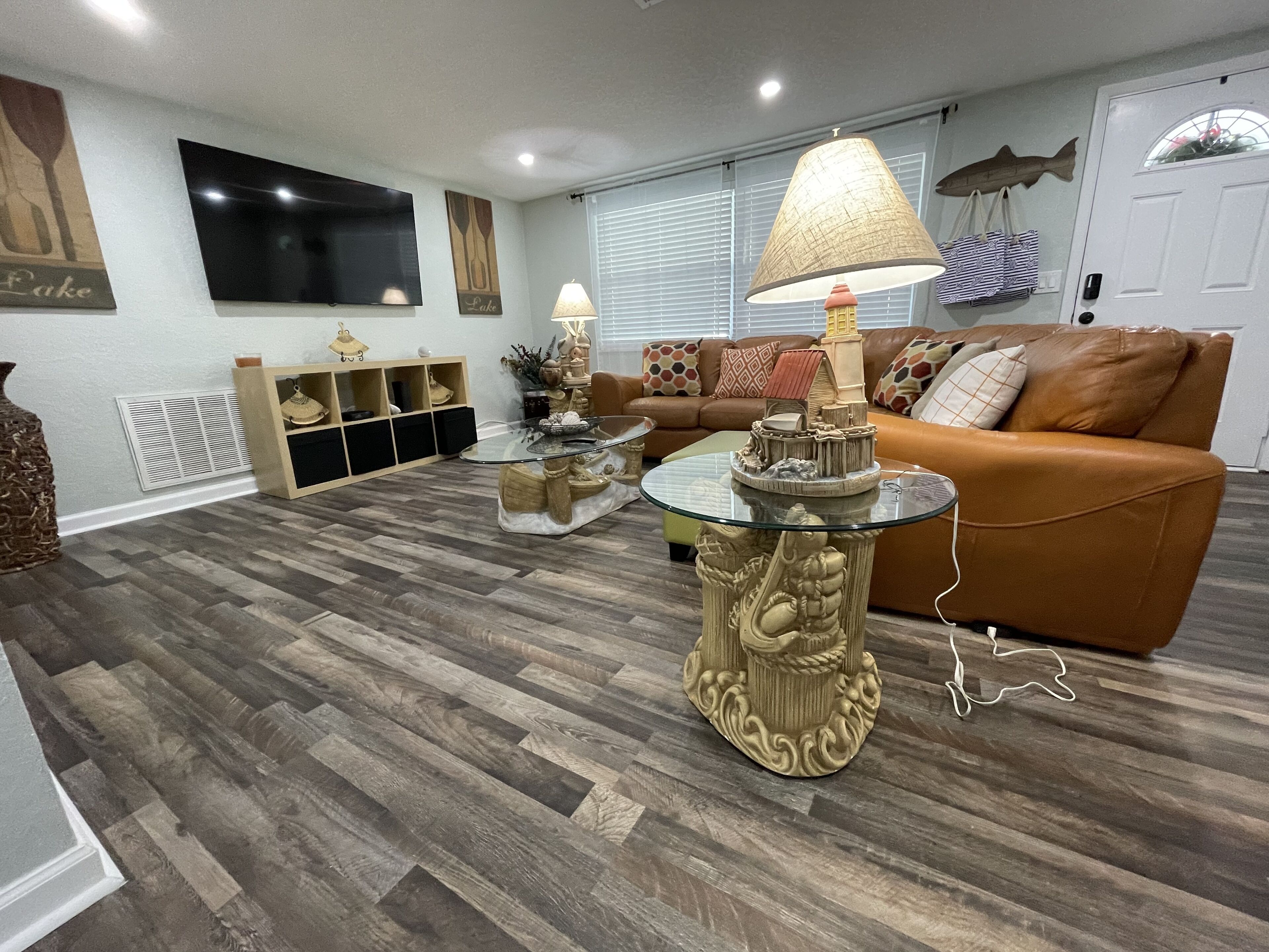 A living room with a brown leather sofa, a glass coffee table, and a decorative lamp.