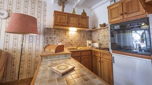 A kitchen with wooden cabinets, a tiled backsplash, a stove, and a sink. - House l'oustaou les 2 oliviers (Moustiers-Sainte-Marie)