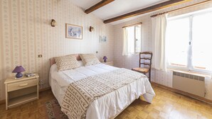 A bedroom with a bed, a nightstand, a chair, a window, and a radiator. - House l'oustaou les 2 oliviers (Moustiers-Sainte-Marie)