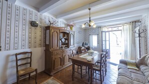 A dining area with a wooden table, chairs, a chandelier, and a television. - House l'oustaou les 2 oliviers (Moustiers-Sainte-Marie)