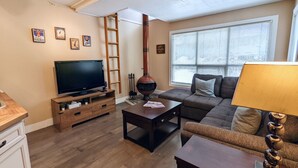 Una sala de estar con televisión, sofá, mesa de centro y chimenea.