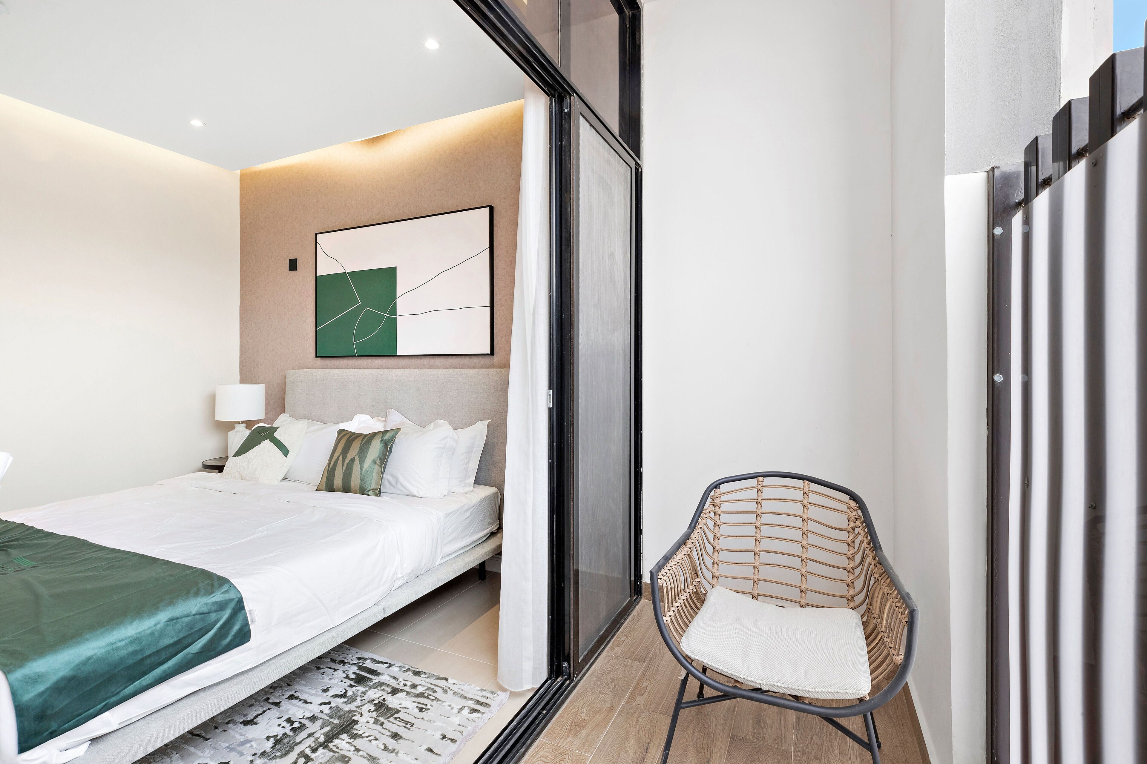 Un dormitorio moderno con una cama, una silla y un cuadro en la pared.