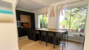 A modern kitchen with a wooden countertop, bar stools, and pendant lighting. - 4 bedroom villa in la baule-escoublac (La Baule-Escoublac)