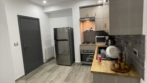 Une cuisine moderne avec des meubles gris, un réfrigérateur en acier inoxydable, un four à micro-ondes et un plan de travail en bois.