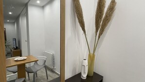 Un intérieur moderne agrémenté d’un grand miroir, d’une console en bois foncé et de quelques brins d’herbe des pampas disposés dans un vase à des fins décoratives.