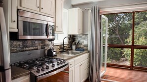 Cocina moderna con estufa a gas, microondas y salpicadero de piedra.