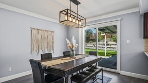 Un comedor con una mesa de madera oscura, sillas negras y una lámpara colgante.