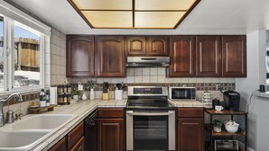 Una cocina moderna con armarios de madera oscura, electrodomésticos de acero inoxidable y un ventanal que proporciona luz natural.
