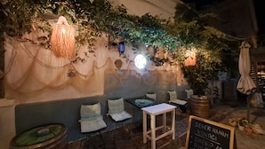 An outdoor seating area with tables and chairs, a chalkboard menu, and decorative plants and lights. - Seher Hanim Konagi (Bozcaada)