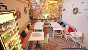 A cozy restaurant with stone walls, wooden tables, and a variety of seating options including a sofa and chairs. - Seher Hanim Konagi (Bozcaada)
