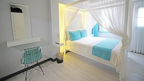 A bedroom with a bed, a nightstand, a chair, a mirror, and a window with curtains. - Seher Hanim Konagi (Bozcaada)