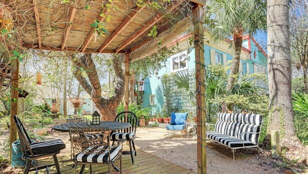 An outdoor patio with a wooden table and chairs, a blue sofa, and a striped bench.