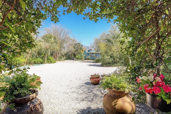 A pathway leading to a house surrounded by greenery and potted plants. - Windmill Gardens Inn "Gallery" by Galveston Bay is a cozy tropical hideaway! (San Leon)