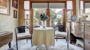 A room with a round table, two chairs, a dresser, and a window with blinds.