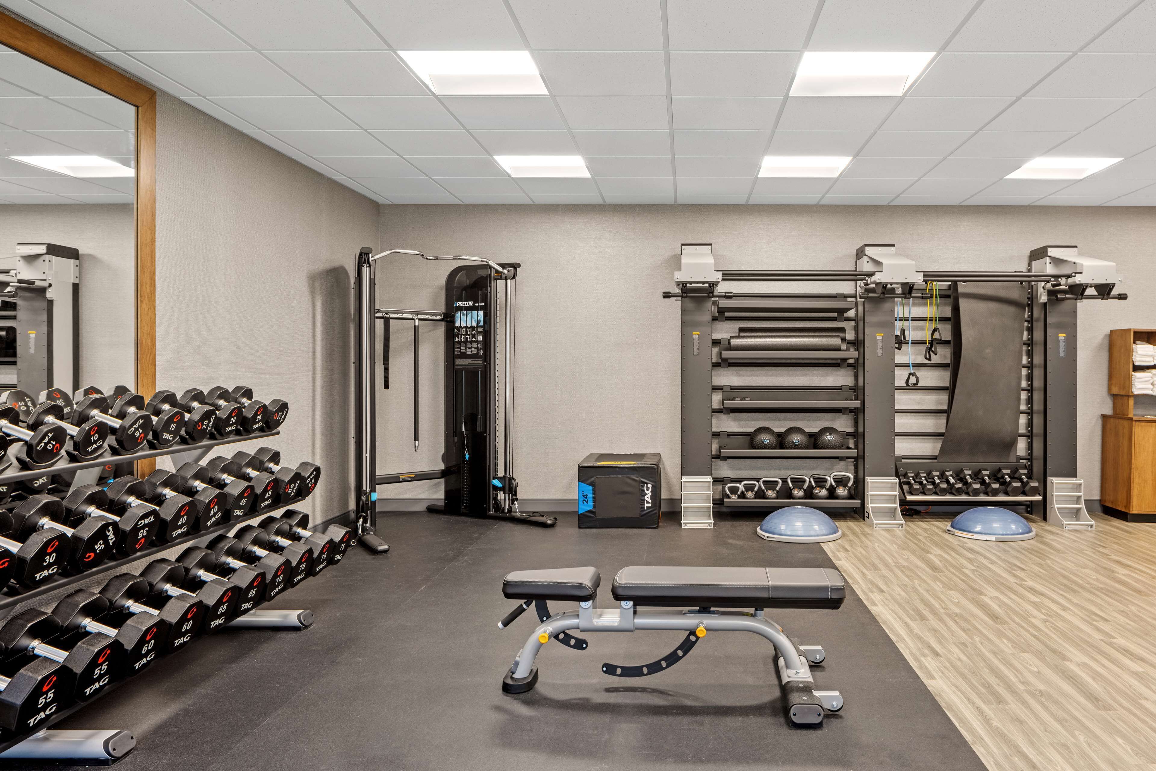 A gym with weightlifting equipment, dumbbells, and exercise machines.
