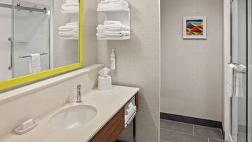Une salle de bain moderne avec un grand miroir, un lavabo, un porte-serviettes et un espace douche.