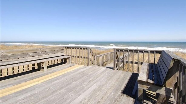 Un paseo marítimo de madera que conduce a la playa, con una vista despejada del océano.