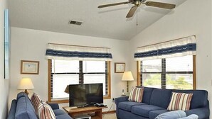 Ein Wohnzimmer mit zwei Sofas, einem Fernseher und einem Deckenventilator.