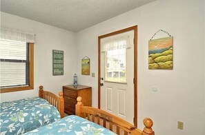 A bedroom with a bed, dresser, and a door with a window. - 4 bedroom, short walk to the beach in Kill Devil Hills! (Kill Devil Hills)