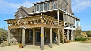A two-story house with a wooden deck and a covered porch. - Gorgeous old nags head oceanfront home with spacious decks and beautiful views! (Nags Head)
