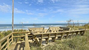 A wooden boardwalk leading to a beach with a clear view of the ocean. - Gorgeous old nags head oceanfront home with spacious decks and beautiful views! (Nags Head)