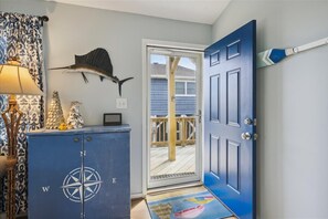 Enter a nautical haven with a traditional blue door, flanked by a compass and nautical art.