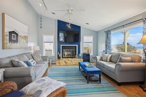 Cozy up by the fireplace in this stylish living room, featuring a large window with a view of the outdoors.