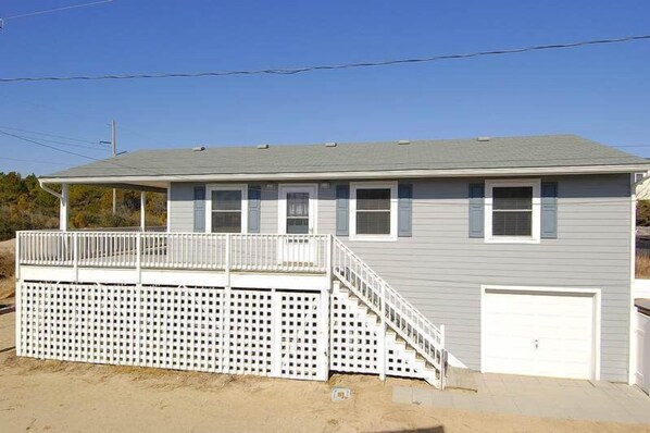 Une maison à deux étages avec un porche couvert, une terrasse clôturée et un garage.