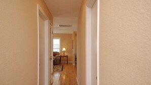 A narrow hallway with wooden flooring and beige walls. - South Nags Head cottage with hot tub! 3 minute walk to the beach. (Nags Head)