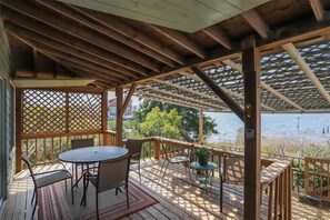 Una terraza de madera con una mesa y sillas, con vista a un cuerpo de agua.