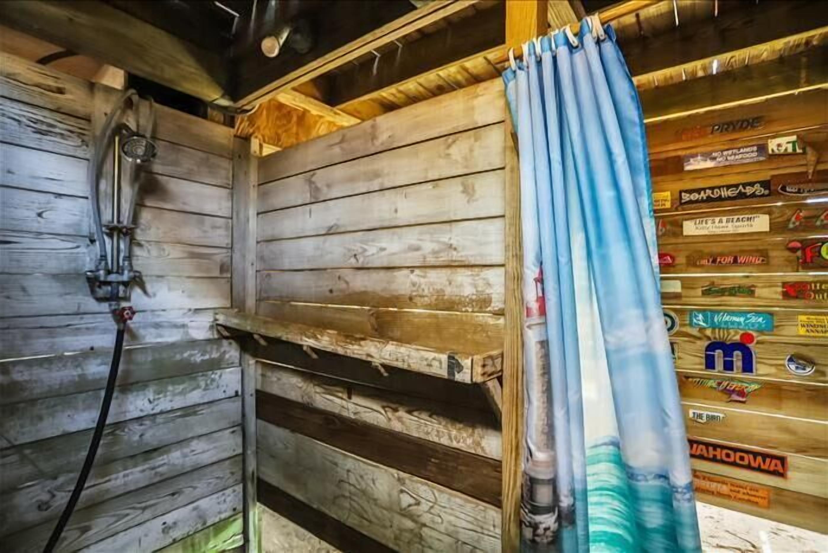A rustic wooden interior with a shower area and a wall decorated with various stickers.