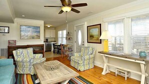 A living room with a ceiling fan, a dining area, and a kitchen in the background. - 5 bedroom, classic old nags head oceanfront home! (Nags Head)