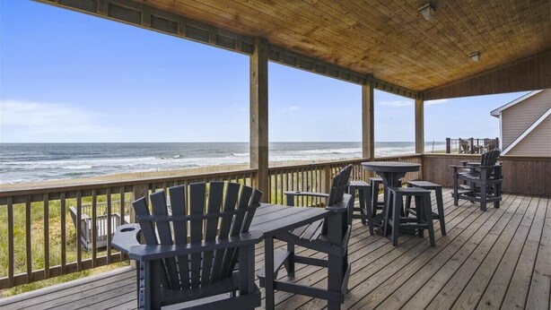 A wooden deck with outdoor seating and a view of the ocean. - Beautiful and classic OBX oceanfront home in KDH! Steps from the Avalon Pier. (Kill Devil Hills)