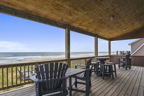 Una terraza de madera con mobiliario exterior y vista al océano.
