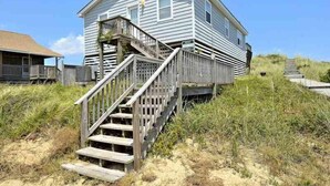 Ein zweistöckiges Haus mit einer Holztreppe, die zu einer Veranda führt.