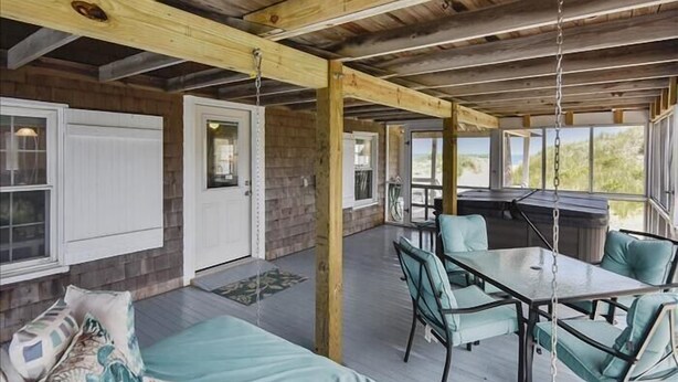 A covered outdoor area with a dining table and chairs, a sofa, and a barbecue grill. - 6 bedroom, classic old nags head style oceanfront with a hot tub! (Nags Head)