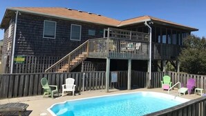 Una casa de madera con piscina, terraza y sillas para exteriores.