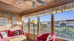 Una habitación acogedora con techo de madera, un sofá rojo, una mesa de madera y amplias ventanas con vistas al exterior.