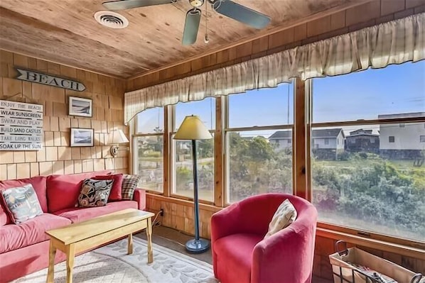 Une pi èce chaleureuse avec un plafond en bois, un canapé rouge, une table en bois et de grandes fenêtres donnant sur l’extérieur.