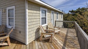 A wooden deck with chairs and a railing.