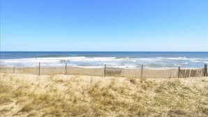 A beach with a wooden fence and sandy dunes. - Oceanfront condo in Kill Devil Hills! (Kill Devil Hills)
