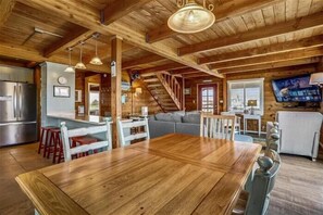 Una cocina amplia con vigas de madera, una gran mesa de comedor de madera y una escalera que conduce a una zona superior.