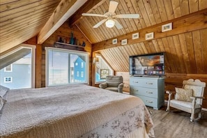 Acogedor dormitorio en el ático con cama, televisor y mecedora.