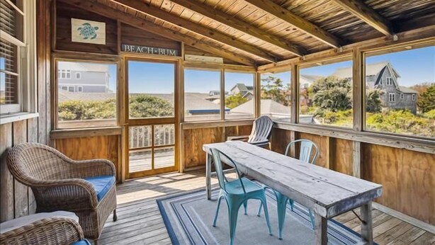 Un espacio al aire libre cubierto con techo de madera, una mesa, sillas y un letrero que dice "Beach Bum".